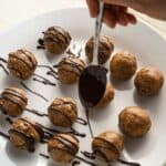 pecan pie truffles rolled into balls on a white plate with chocolate being drizzled over the top with a spoon